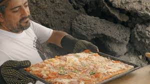 Man cooking pizza on heat from lava from Volcano de Pacaya.