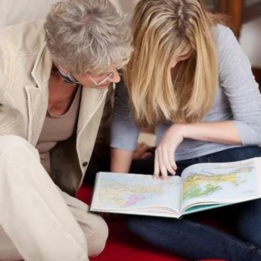 Grandmother and Granddaughter looking at an atlas.